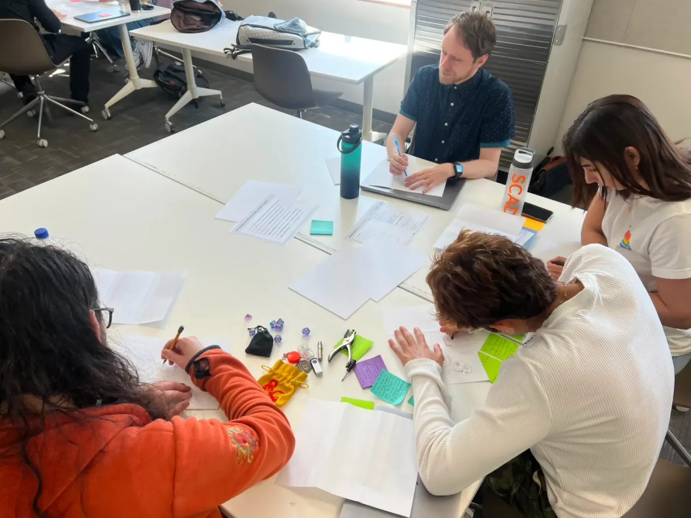 A pod sketching interface ideas with notes and printed research