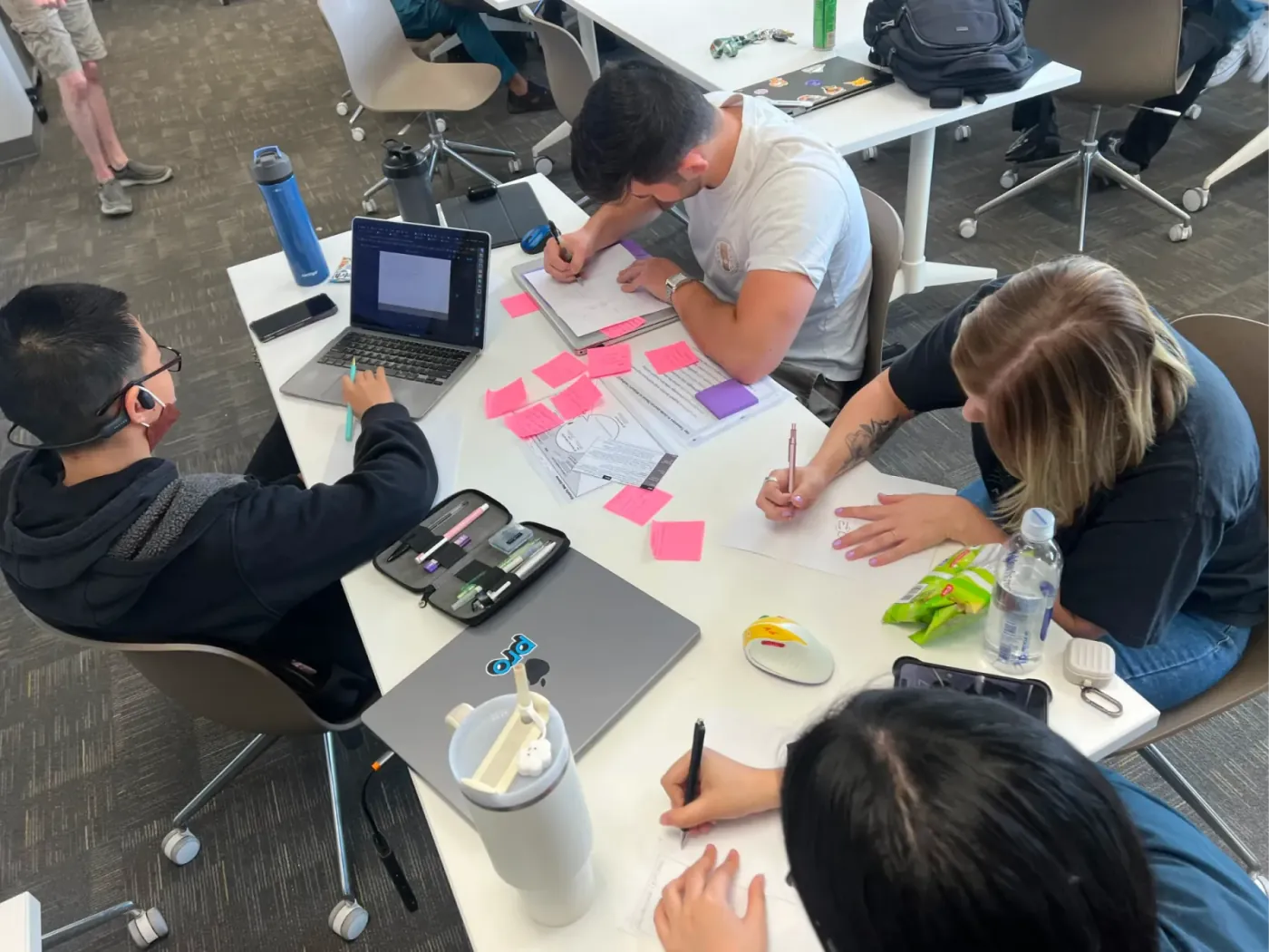 Four team members sketching concepts at a table covered in sticky notes